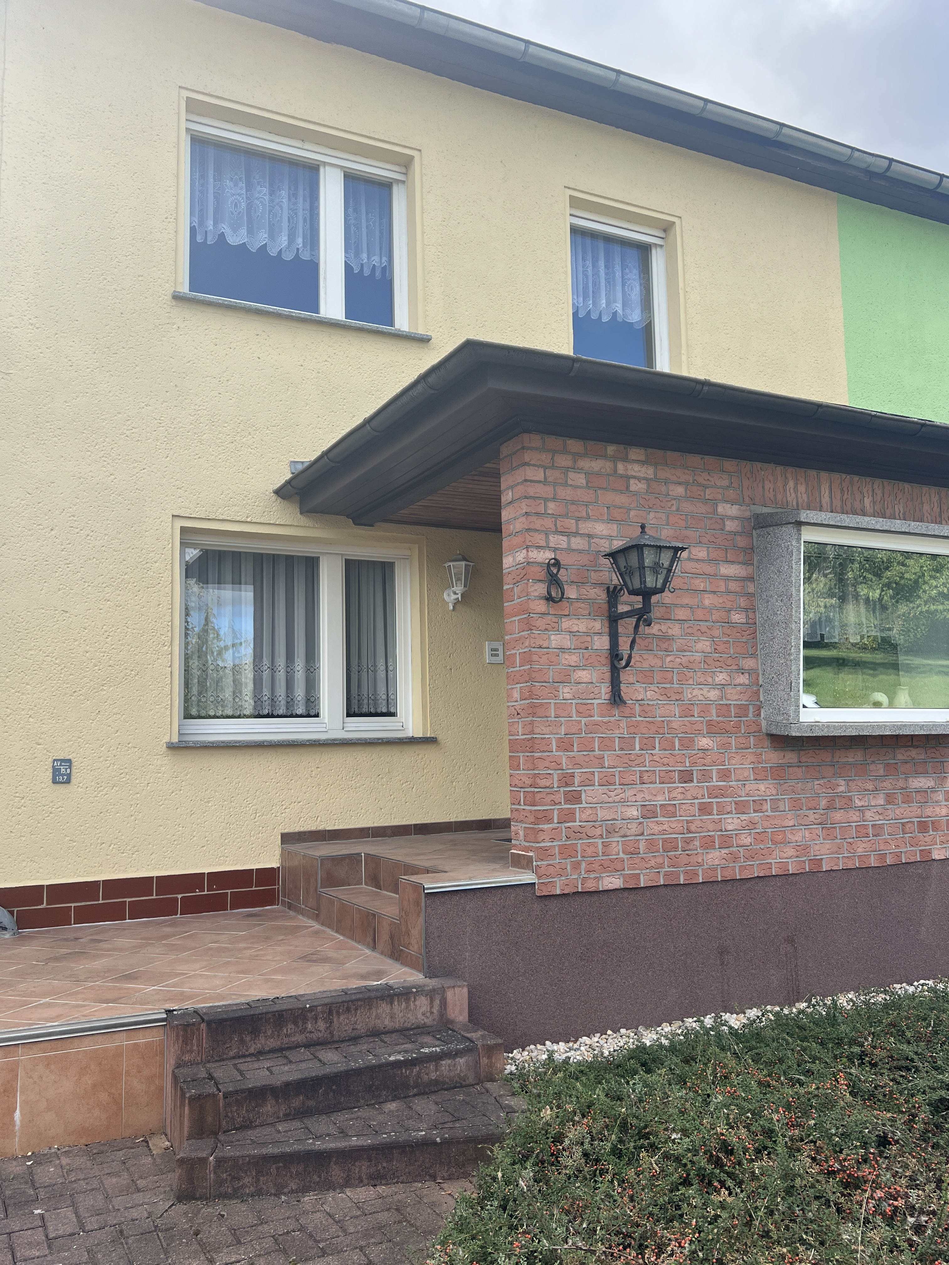 Neues Titelbild von Bobbau: Eingangsbereich eines renovierten Einfamilienhauses mit gelber Fassade und Backstein-Elementen