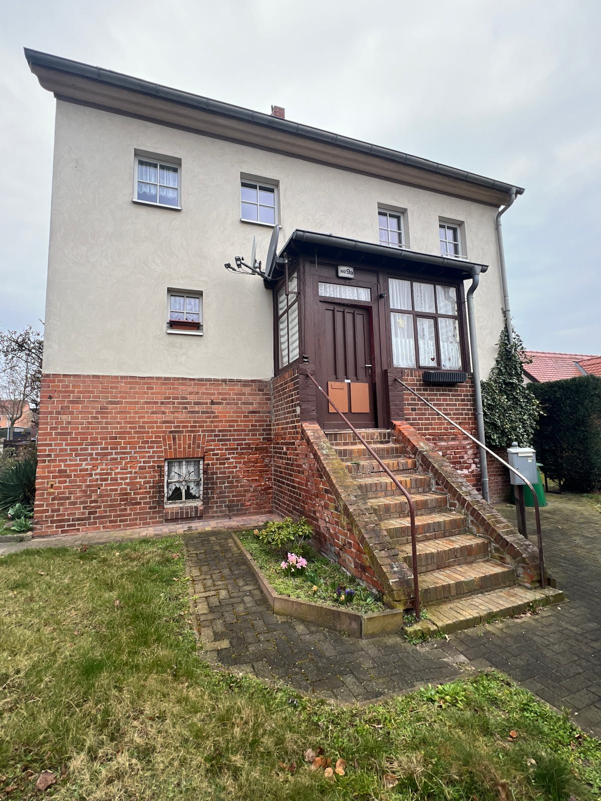 Eingangsbereich eines Einfamilienhauses mit Backsteinfassade und Treppe, titelbild-neu