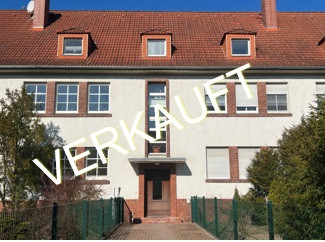 Mehrfamilienhaus mit Schriftzug verkauft auf dem Bild