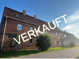 Verkauftes Mehrfamilienhaus in Prussendorf am Teich mit Backsteinfassade unter blauem Himmel
