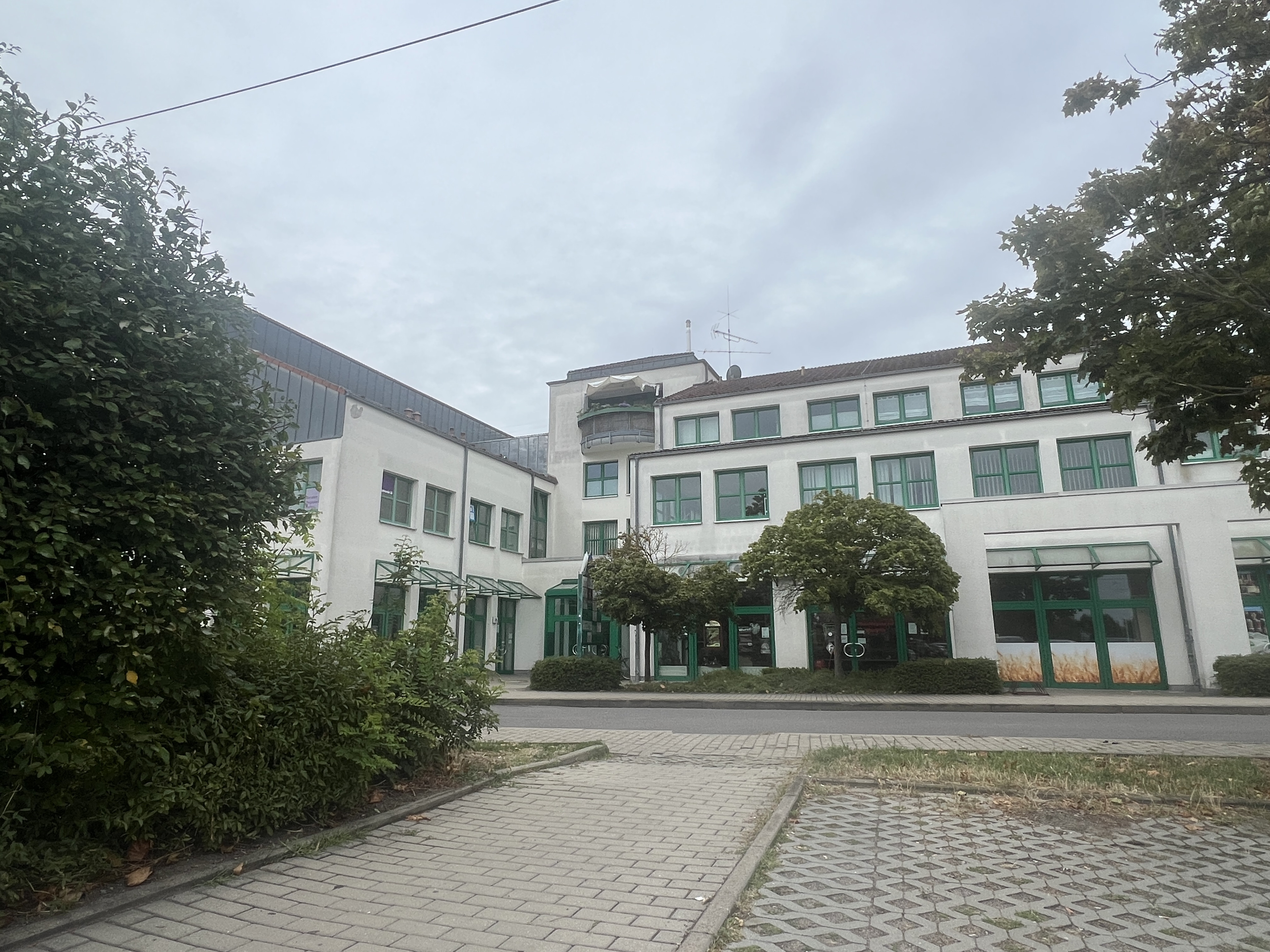 Modernes Bürogebäude mit weißen Fassaden und grünen Fensterrahmen an einem bewölkten Tag