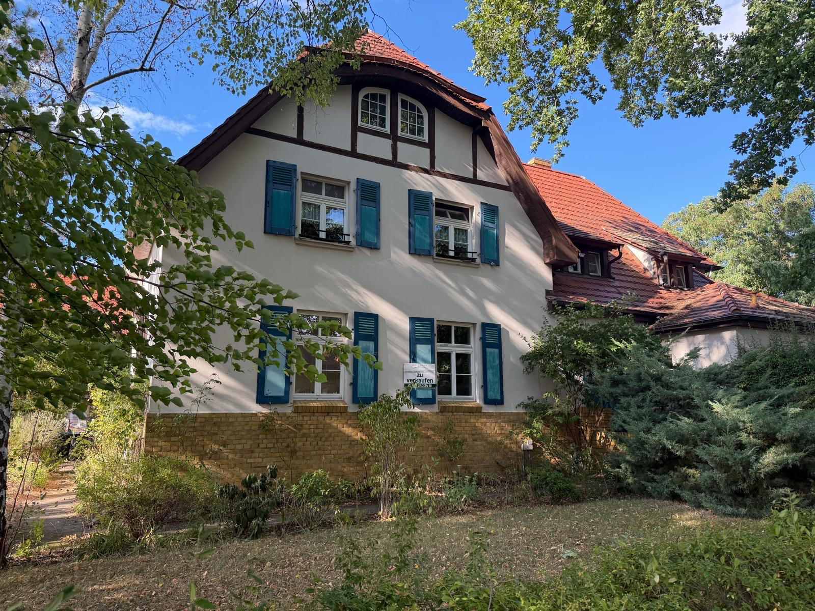 Titelbild neu: Charmantes Einfamilienhaus mit blauen Fensterläden und rotem Dach, zu verkaufen