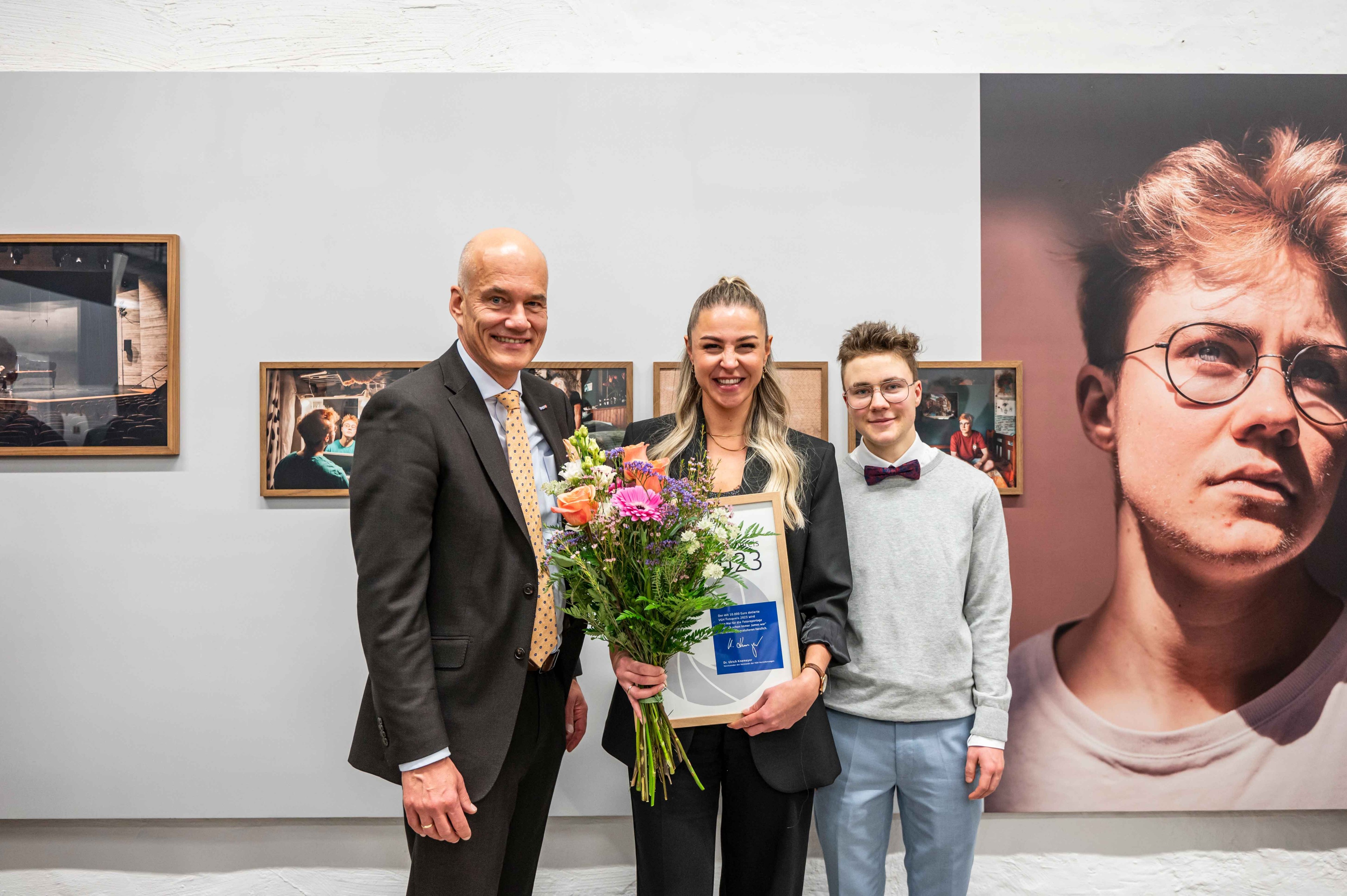 Studierende der Hochschule Hannover haben alljährlich die Chance, mit dem VGH-Fotopreis ausgezeichnet zu werden. Auf dem Bild zu sehen sind VGH-Vorstandsvorsitzender Dr. Ulrich Knemeyer, die Gewinnerin 2023 Jana Mai und der von ihr portraitierte James.  F