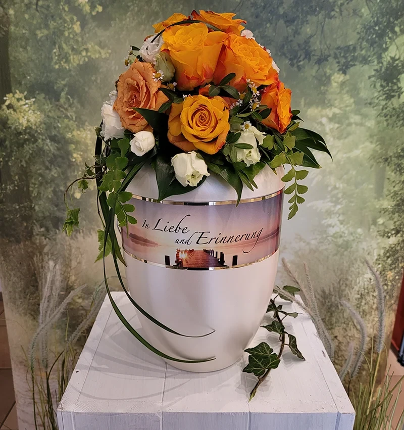 Bestattungen Urne mit Blumen und Aufschrift 'In Liebe und Erinnerung'