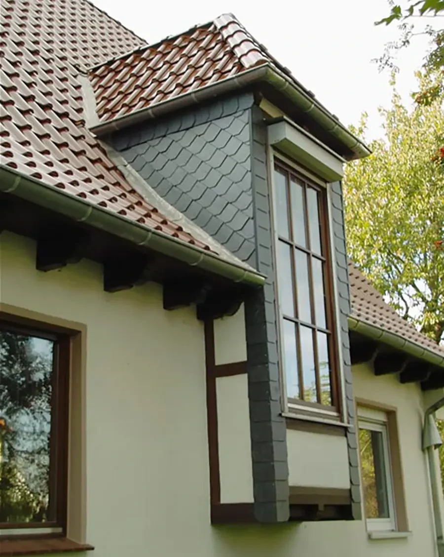 Moderne Hausfassade mit Dachschindeln und großem Fenster