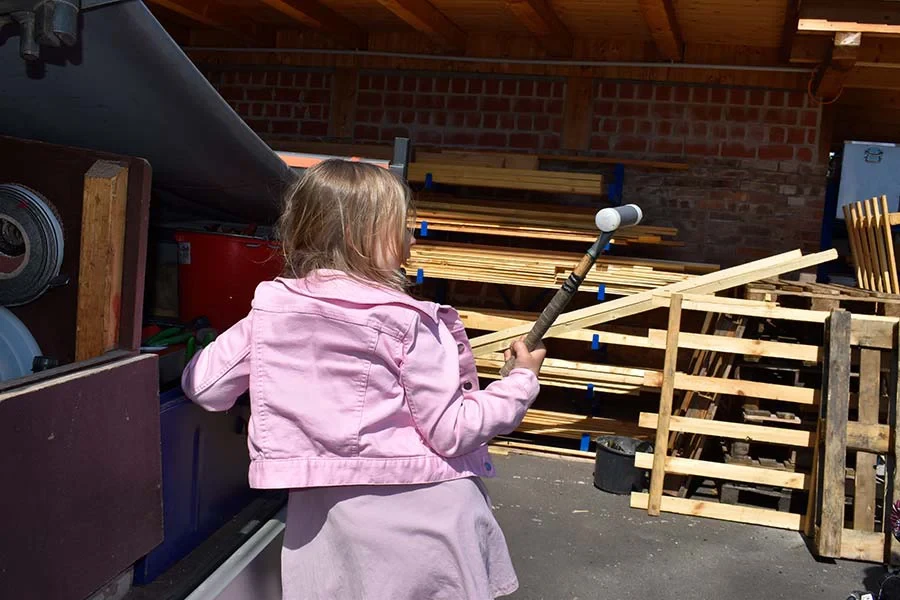 Kind mit Holzhammer bei Kleinreparaturen im Freien