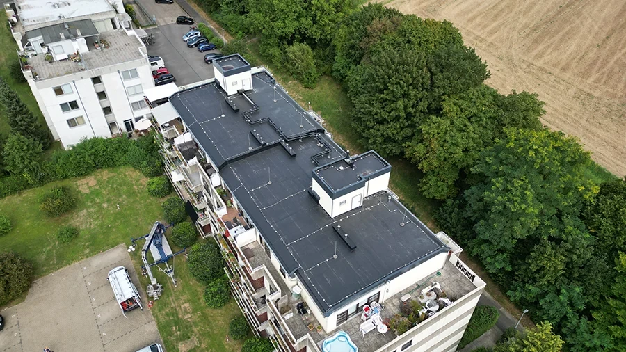 Drohnenaufnahme eines Flachdachs eines Wohngebäudes mit umliegender Vegetation