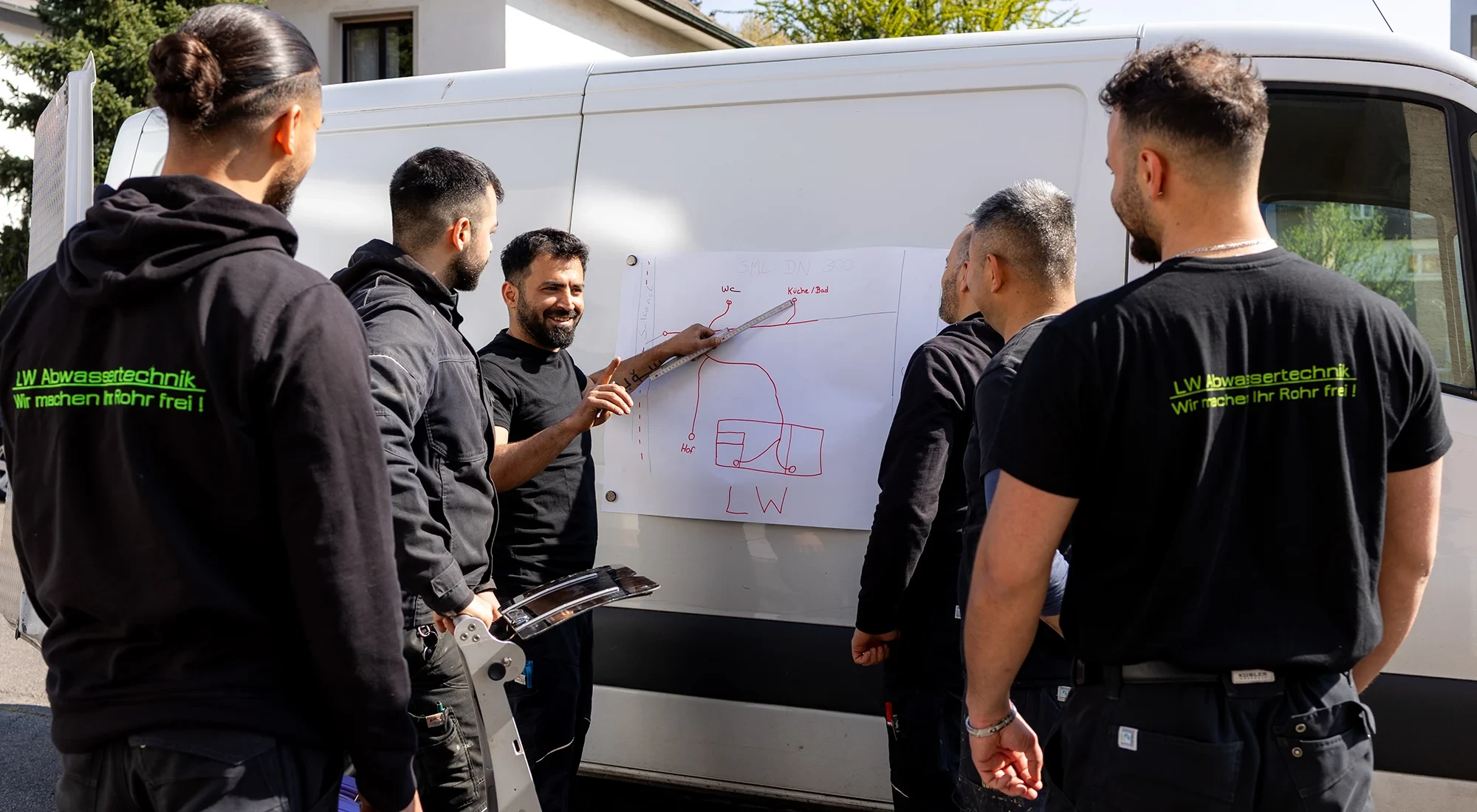 Gruppe von Handwerkern bei der Planung von Reparaturen an einem Lieferwagen