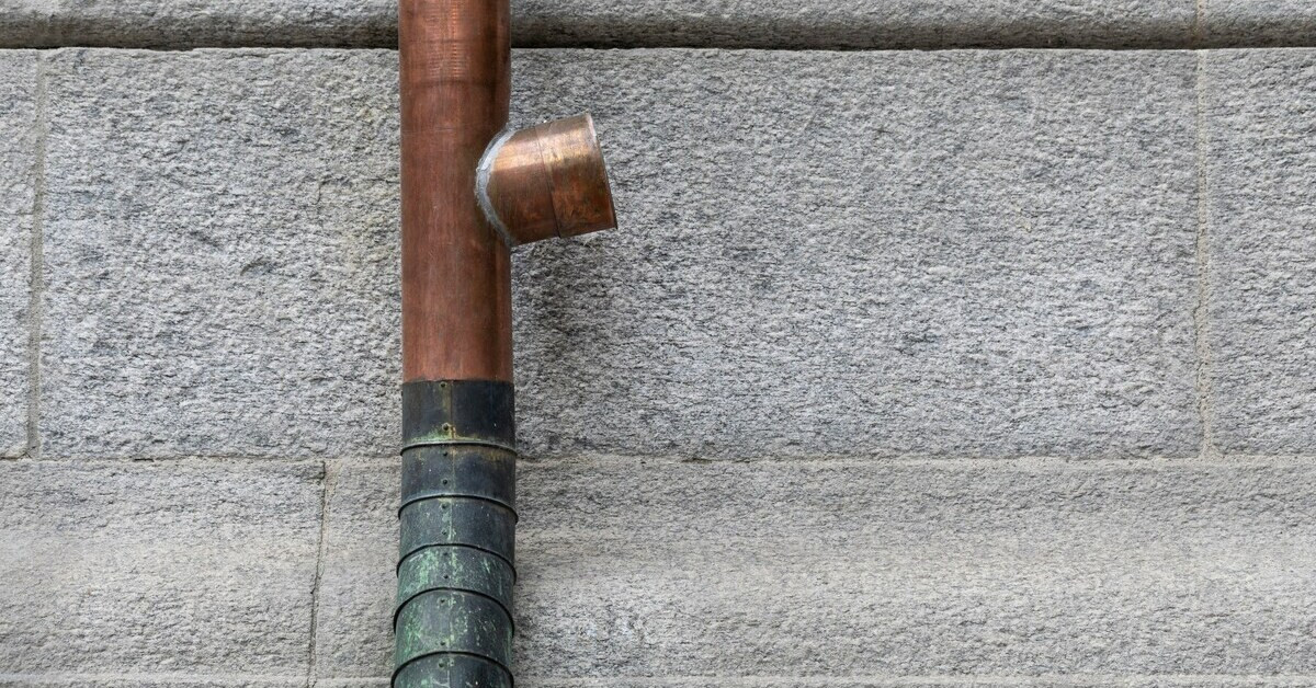 Rohr mit ersetztem Teilstück vor einer Steinwand