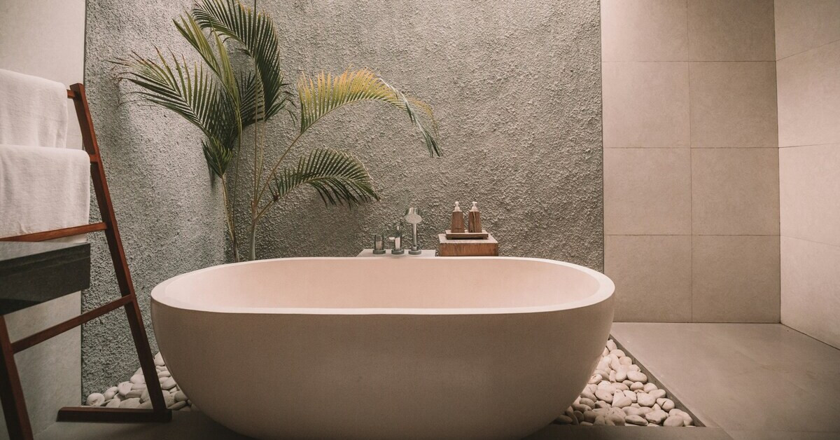 Moderne Badewanne in stilvollem Badezimmer mit Pflanzen und Naturstein
