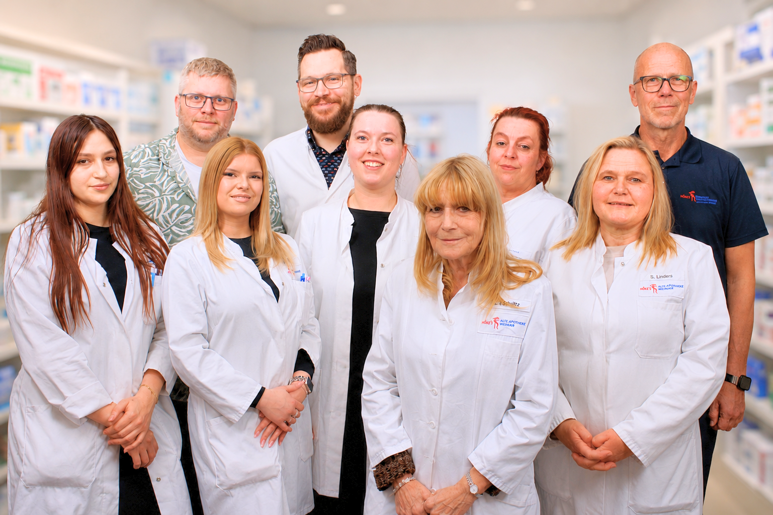 Team Sani in weißen Kitteln in einer Apotheke