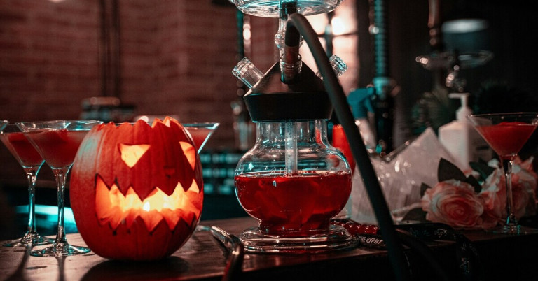 Halloween-Drinks: Roter Cocktail und Kürbis-Deko für die Halloween-Party Halloween-Drinks mit rotem Cocktail und leuchtendem Kürbis auf einer Bar