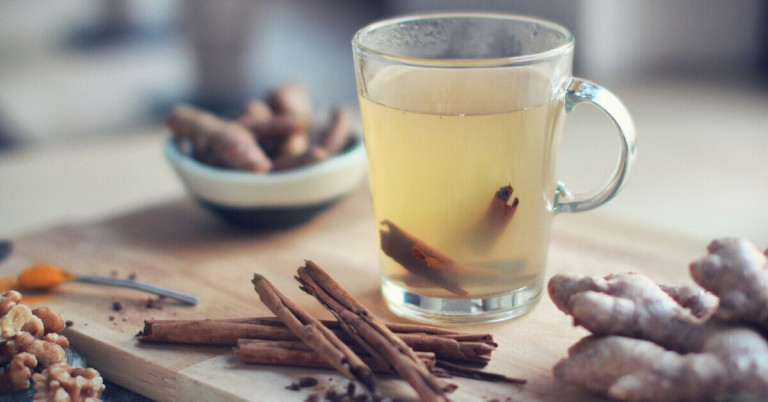 Herbstdrink – würziges Heißgetränk mit Zimtstangen für den Herbst Herbstdrink mit Zimtstangen und Gewürzen in einem Glas