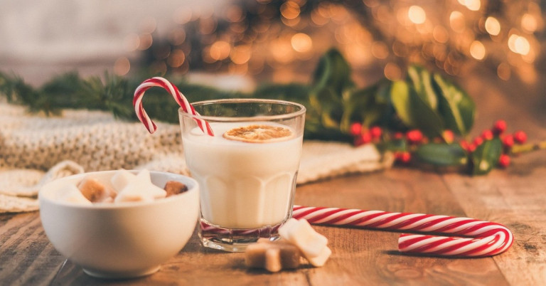 Eierpunsch – traditionelles Weihnachtsgetränk im Glas mit Zuckerstange Eierpunsch im Glas mit Zuckerstange und Weihnachtsdekoration