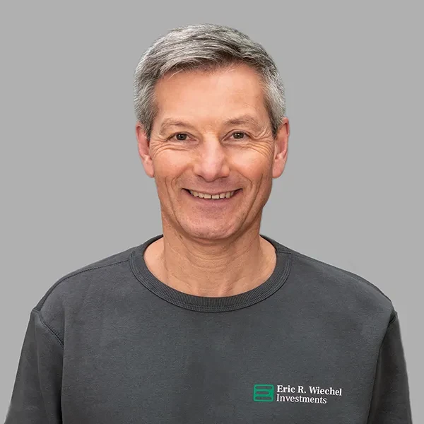 Jens Kreutzfeldt mit Pullover von Eric R. Wiechel Investments vor grauem Hintergrund