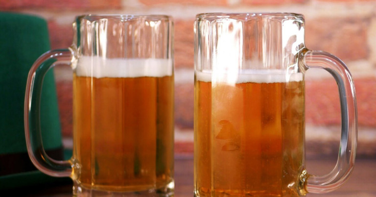 Zwei gefüllte Bierkrüge mit Bier vor einer Backsteinwand