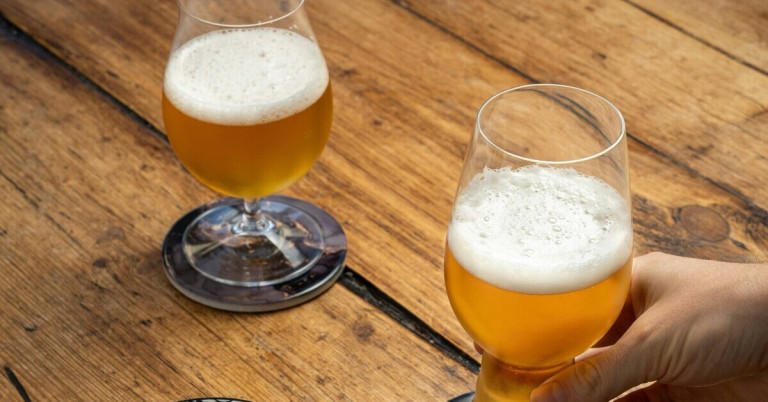 Zwei gefüllte Biertulpen-Gläser mit Bier auf einem Holztisch