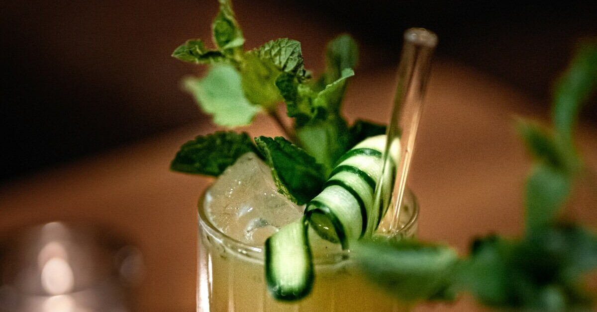 Erfrischender Cocktail mit Minze und Gurke, garniert mit Eis und Trinkhalm