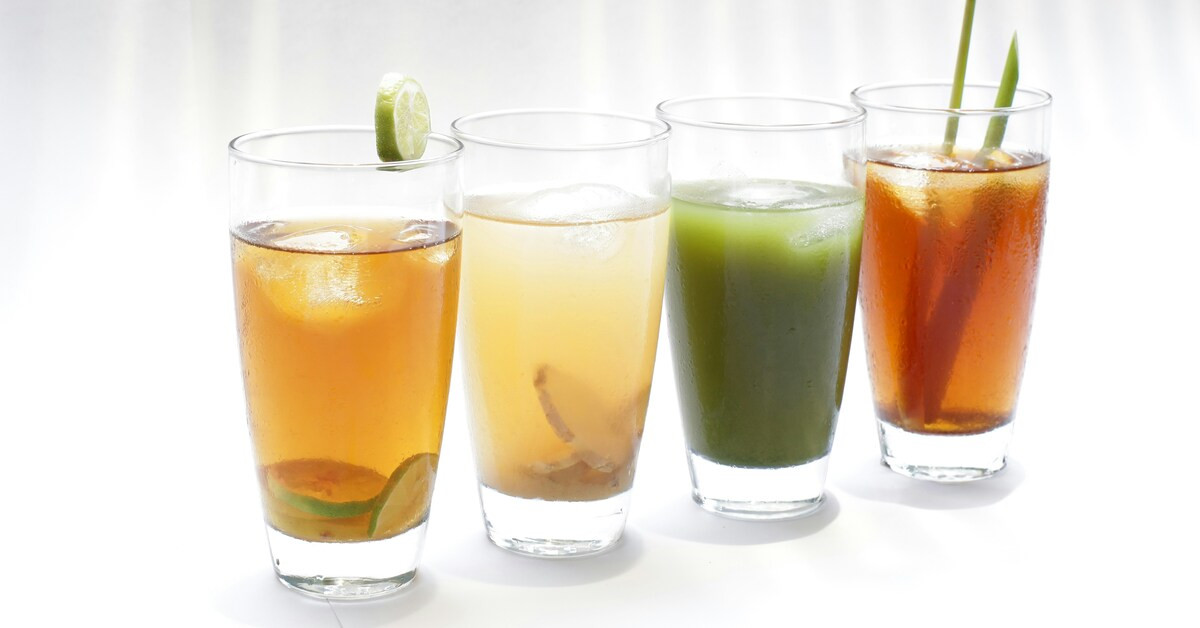 Bunte Drinks in Gläsern mit Eis und Limettenscheibe auf weißem Hintergrund