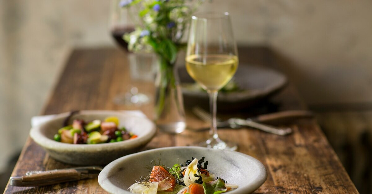 Food Pairing: Feines Gericht mit passendem Glas Wein auf einem Holztisch