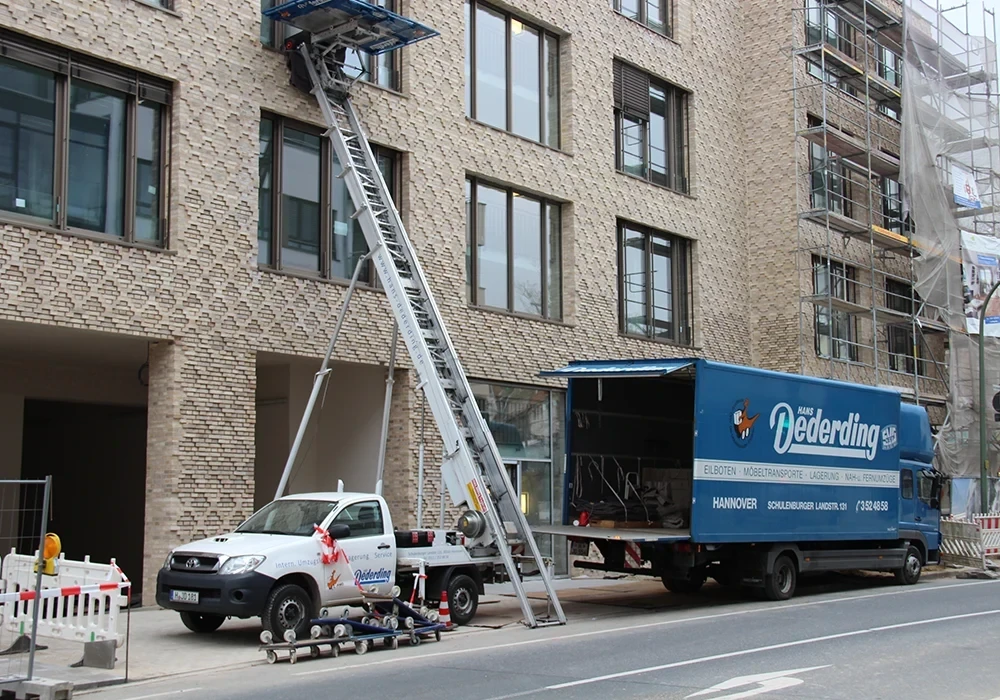 Büro Firmenumzüge mit Möbellift und Umzugswagen vor Bürogebäude