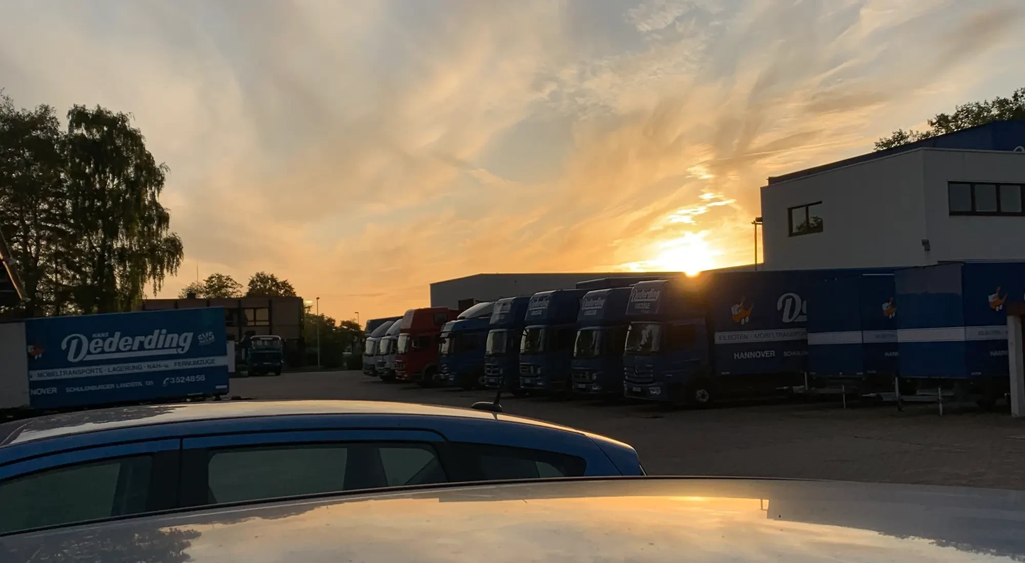 LKW-Flotte auf einem Firmengelände bei Sonnenuntergang