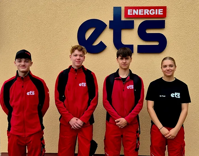 Lehrlinge 2025 bei ets Energie – Auszubildende vor dem Unternehmenslogo Lehrlinge 2025 der ets Energie in Arbeitskleidung vor dem Firmenlogo