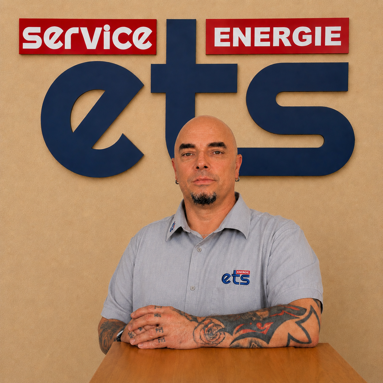Mitarbeiter von ets Energie Service mit Tätowierungen am Arm vor Firmenlogo
