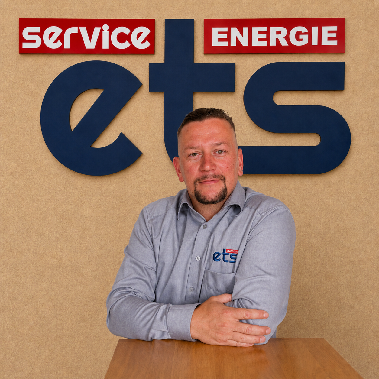 Mitarbeiter von ets Energie Service sitzt am Tisch vor Firmenlogo