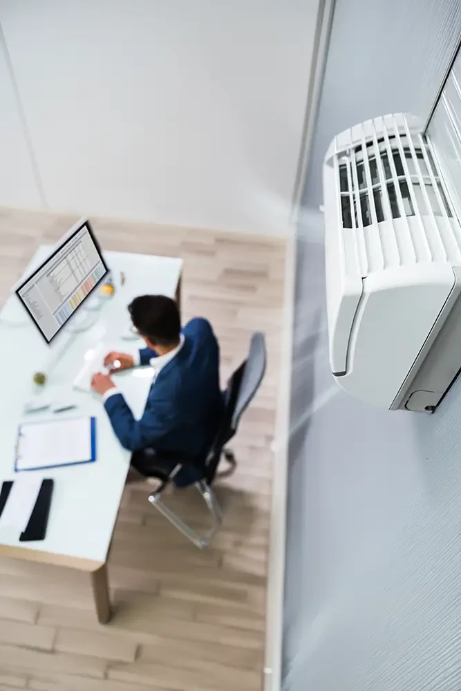 Gewerbeklimaanlage in einem modernen Büro, Mann arbeitet am Schreibtisch am Computer