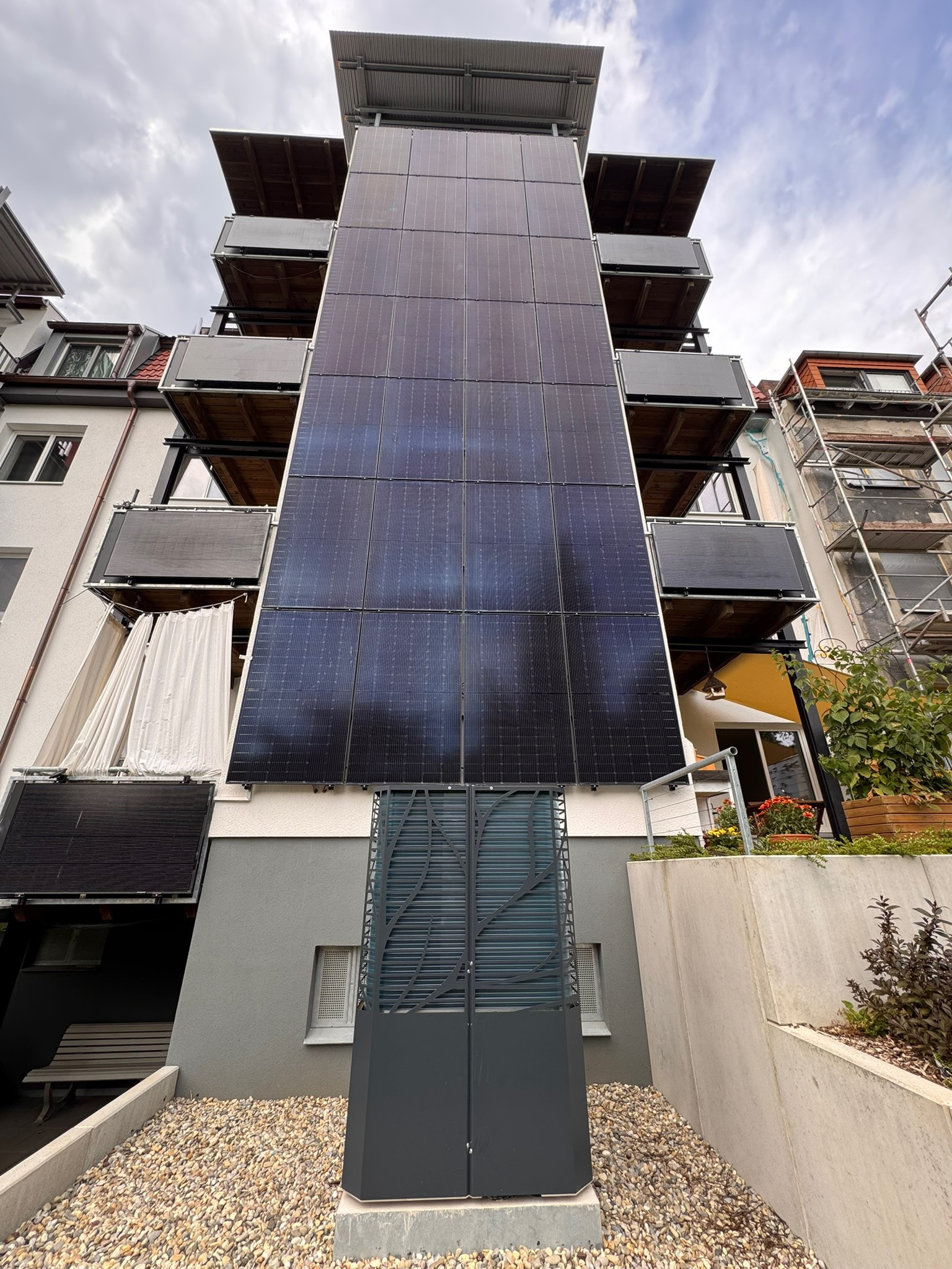 Mehrgeschossiges Wohnhaus mit vertikal installierten Solarpaneelen an der Fassade
