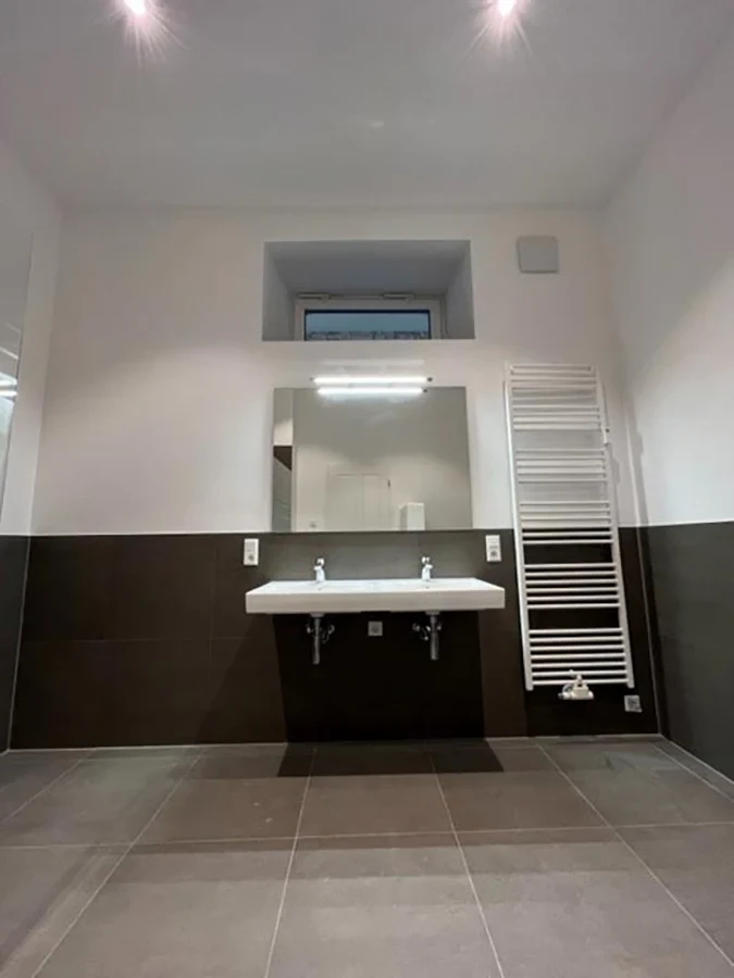 Modernes Badezimmer nach erfolgreicher Badsanierung mit Doppelwaschbecken und Handtuchheizkörper