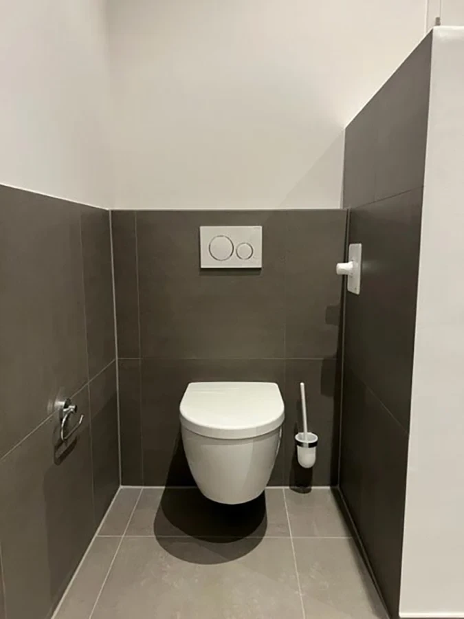 Moderne Badsanierung mit wandhängender Toilette und grauen Fliesen