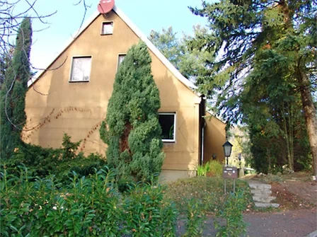 Braunes Haus mit Garten und Bäumen