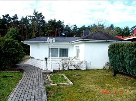 Weißer Bungalow mit Garten und Pflastersteinweg