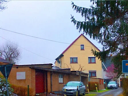 Gelbes Haus mit Garagen und Baum im Vordergrund