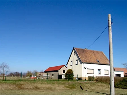 Weißes Haus mit braunem Dach unter blauem Himmel