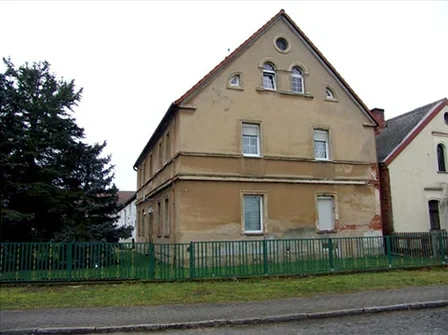 Gelbes Haus mit grünem Zaun und Wiese