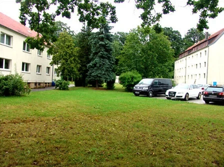 Hellgelbe Häuser mit rotem Dach und großer Wiese