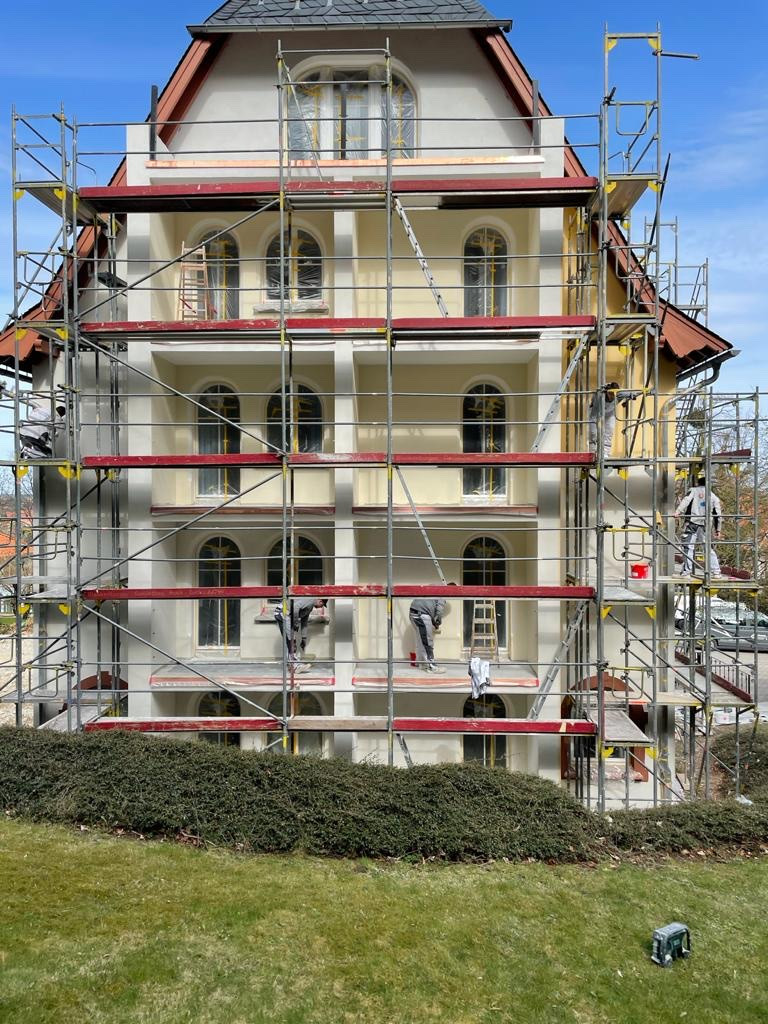 Fassaden-Malerarbeiten an einem mehrstöckigen Gebäude mit Gerüst und Handwerkern
