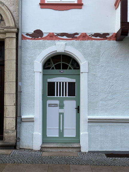 Malerarbeiten an einer Hausfassade mit dekorativer Haustür und Stuckverzierung