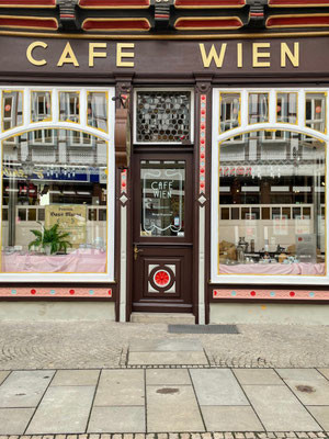 Malerarbeiten an der Fassade eines Cafés, detailreiche Fensterrahmen und Tür mit dekorativen Elementen