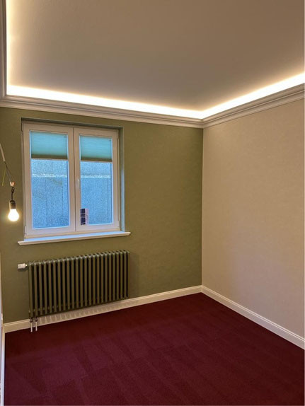 Frisch gestrichener Raum mit modernen Malerarbeiten, grüne Wandfarbe und LED-Deckenbeleuchtung