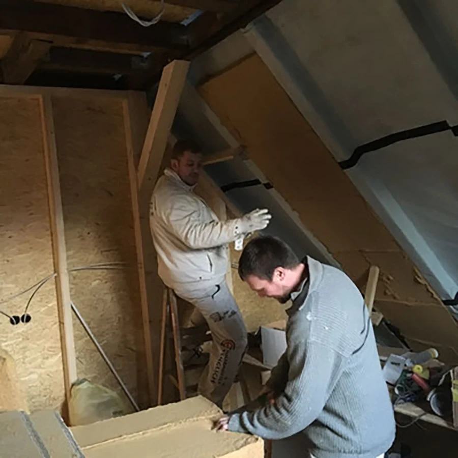 Energetische Sanierung eines Dachbodens mit zwei Handwerkern bei der Dämmung der Dachschrägen