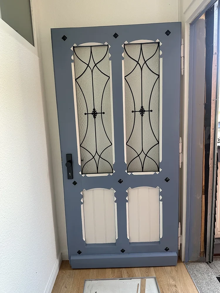 Restaurierte Haustür mit dekorativen Glaseinsätzen und schmiedeeisernen Elementen