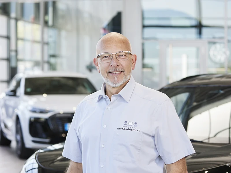 Christian Plura im Autohaus, Porträtaufnahme vor Fahrzeugen