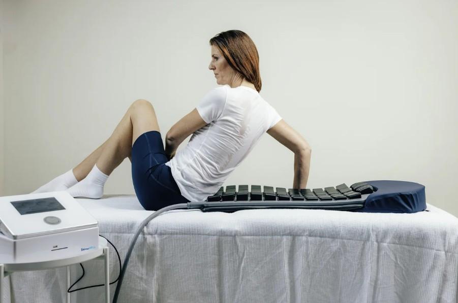 Person bei einer StimaWELL Behandlung auf einer Therapieliege mit Stimawell System