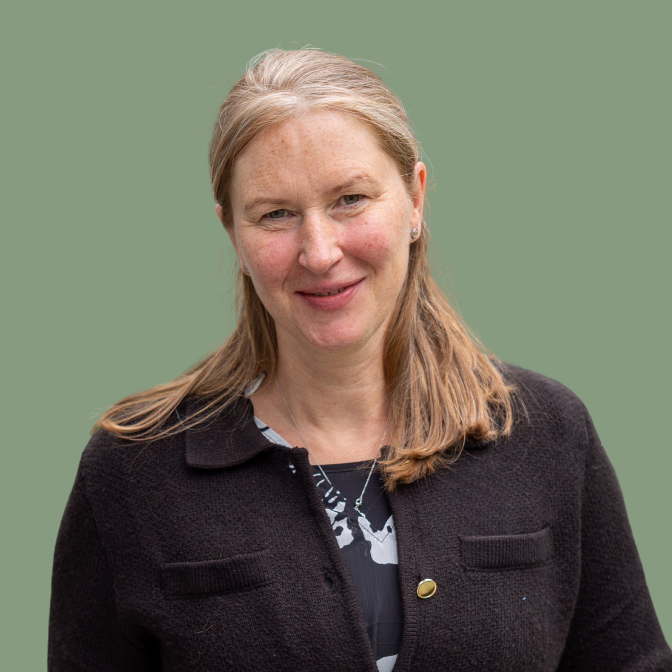 Porträt einer Frau mit blonden Haaren, schwarzer Jacke und grünem Hintergrund