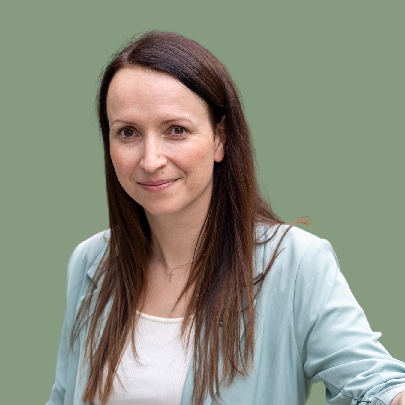 Frau mit langen braunen Haaren und hellblauem Blazer vor grünem Hintergrund