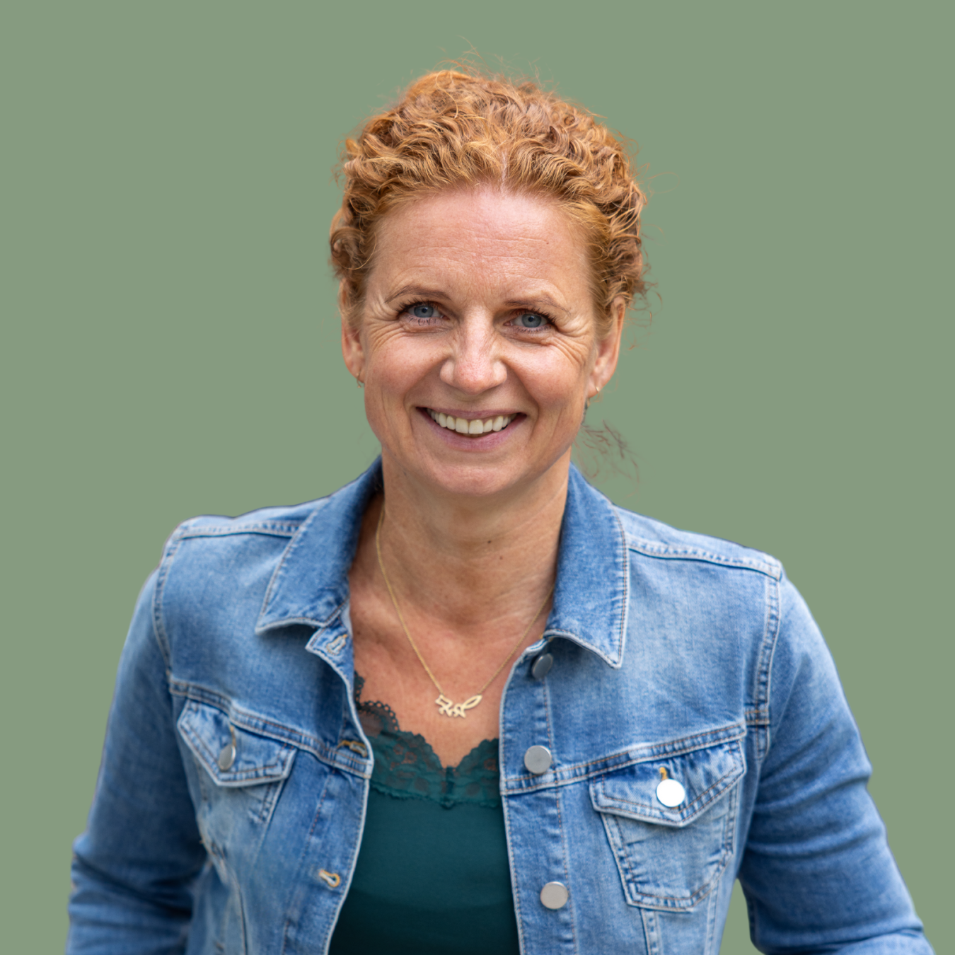 Frau mit lockigen roten Haaren und Jeansjacke vor grünem Hintergrund